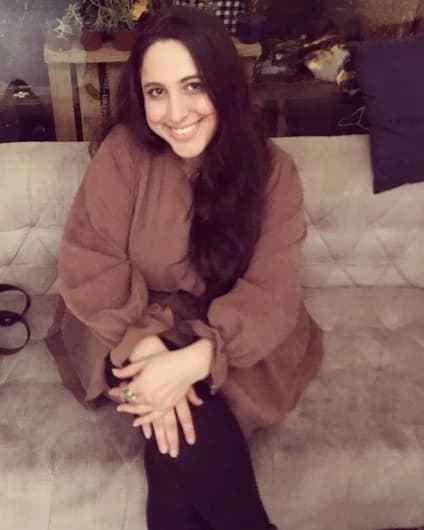 Luiza Fernandes Bezerra sentada num sofá, sorrindo, de blusa cor de barro.